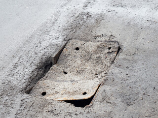 The bent and deformed road hatch creates an emergency situation on the road. Safe roads concept.