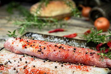 Raw pork tenderloin with rosemary and spices in the kitchen