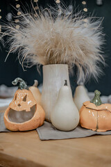 Figurines of a pumpkin made of clay against the background of a bouquet