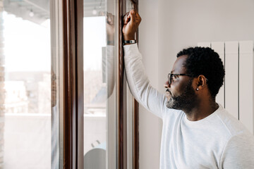 Black bearded man wearing eyeglasses looking in window