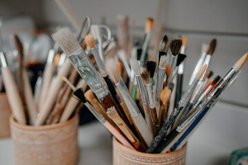 Paint brushes in a clay vase