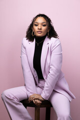 Editorial portrait of a confident young black successful business woman in a pink studio