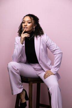 Editorial portrait of a confident young black successful business woman in a pink studio