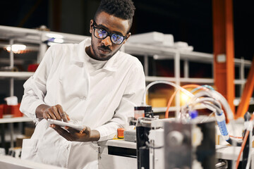 African engineer programming equipment with tablet at factory