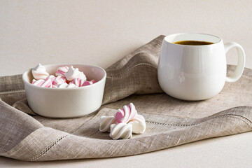 Hot fragrant coffee and sweet marshmallow in a white bowl on a linen serving napkin
