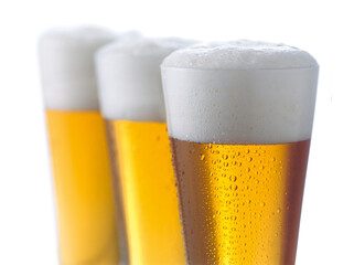 close-up 3 volle Gläser Bier im Anschnitt mit Schaumkrone vor weißem Hintergrund