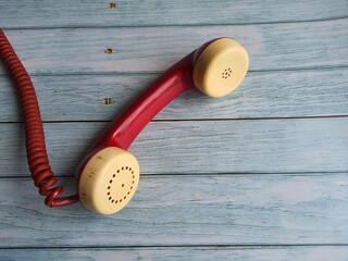 Retro styled telephone, red color, isolated on a wooden table.