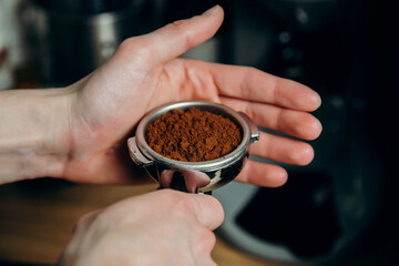 Barista holding portafilter with ground coffee in cafe for prepare to make coffee.