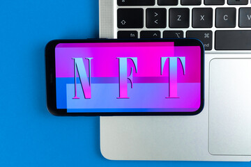 NFT non fungible token background. Modern blockchain technology, future of crypto art and crypto currency. Mobile phone on laptop keyboard, top view photo