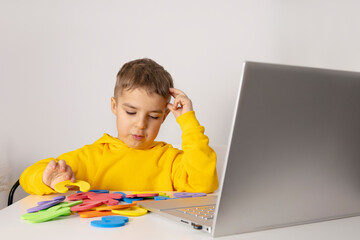 Adorable, cute, little boy learning alphabet online, with laptop at home. Child using e-learning...