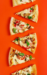 Assorted slices of pizza placed vertically on vibrant orange background