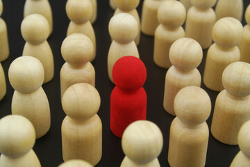 Individuality, unique and different concept. Red wooden figure in crowd of wooden people figures.