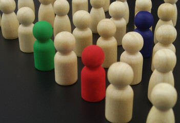 Crowd of wooden people figures, some figures colored close up. Individuality concept.