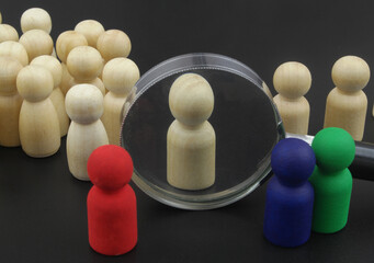 Colored figures choosing and check personnel. Wooden figures under magnifying close up. background....