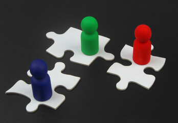 Colorful wooden people figures on white puzzles. Cooperation, agreement, team building, teamwork concept.