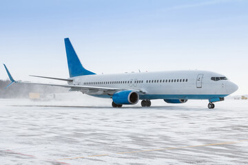 Taxiing of a passenger airliner on the airport apron in a snow blizzard
