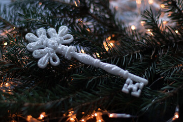 Christmas toy, a white key with silver sparkles on a Christmas tree branch. Bokeh background...