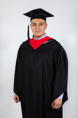 Male graduate student in mortarboard and bachelor gown white background