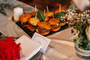 A gourmet platter of mini burgers served on a stylish black tray.