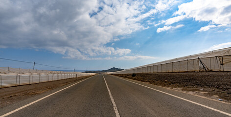 view of a highway passing through endless large greenhouses made of plastic in the waterless desert of southern Spain