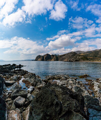 Fototapeta na wymiar secluded rocky cove on a wild mountainous coastline with rocks and tidal pools in the foreground