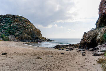 Fototapeta na wymiar secluded sandy beach on a wild mountainous coastline with rocks