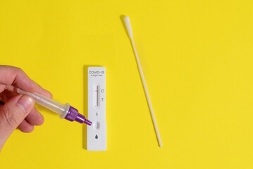 Male hand pouring dropper fluid into an antigen test to see if it is positive or negative for...
