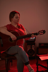 Obraz premium Woman playing acoustic guitar in a retro vintage room.