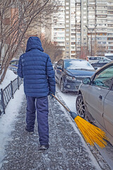 A man clears the sidewalk of snow on a winter day
