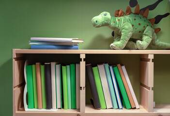 Shelf with books, textbooks and a toy dinosaur in the children's room.