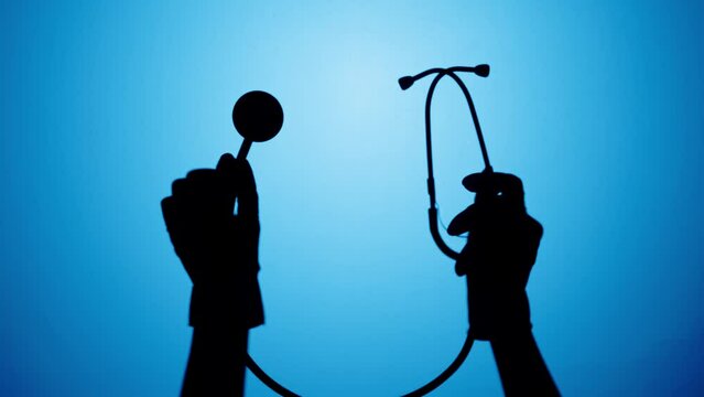 Shadow of stethoscope on blue neon background. Doctor holding medical equipment close-up. Healthcare and medicine concept.