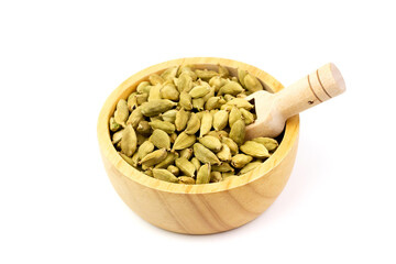 Green Cardamom on wooden bowl with scoop isolated on white background. Green cardamom is a fragrant herb used as an ingredient for cooking. 
