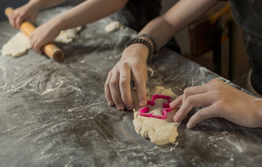 a boy and a girl brother and sister make cookies from dough in the kitchen using a mold.