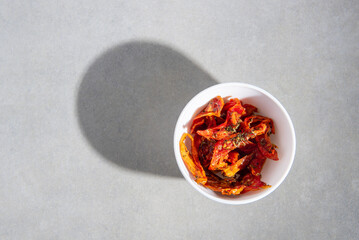 Obraz na płótnie Canvas dried tomatoes with spices in a white plate on a gray concrete background