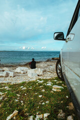 man sitting near car at seaside. road trip concept