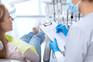 Dentist writing results of patient's examination at appointment