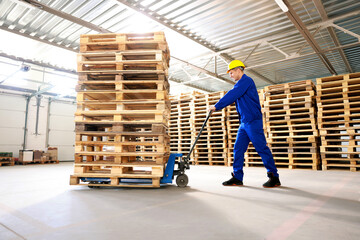 Worker moving wooden pallets with manual forklift in warehouse © New Africa