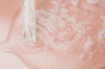 Transparent cosmetic gel in a Petri dish on a pink background. Laboratory research and development of cosmetic body care products. Close-up - the structure of the gel.