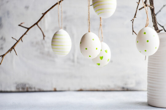 Painted Easter egg decorations hanging on branches in a vase
