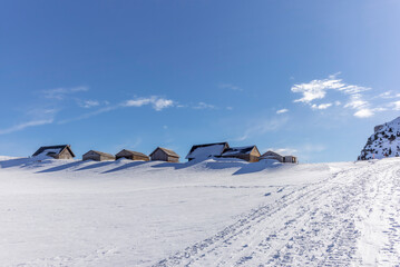 Isolated summer chalet and farm stables high up on the Swiss Alps covered in fresh powder snow near the Kamor peak in Appenzell