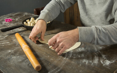 a young man  rolls out the dough for cookies and pie with a rolling pin in the kitchen.