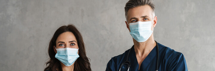 Two confident doctors in medical masks standing