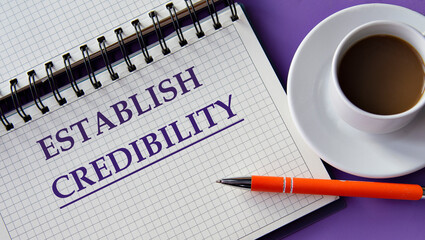 ESTABLISH CREDIBILITY - words in a white notebook on a purple background with a cup of coffee