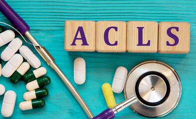 ACLS - acronym on wooden cubes on a blue background with a stethoscope and tablets