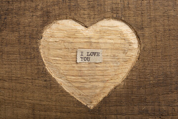 I love you - tiny typed text note close up. Valentines Day greetings concept. Carved heart shape on...