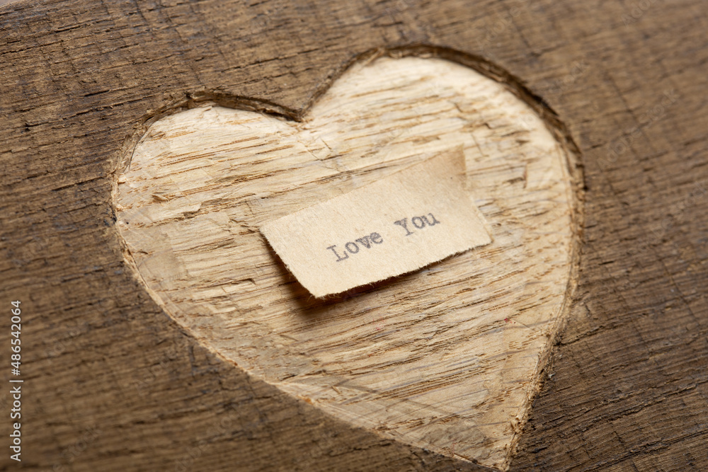 Fototapete love you - tiny typed text note close up. valentines day greetings concept. carved heart shape on wo