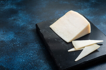 Hard goat cheese on marble board. Blue background. Top view. Copy space
