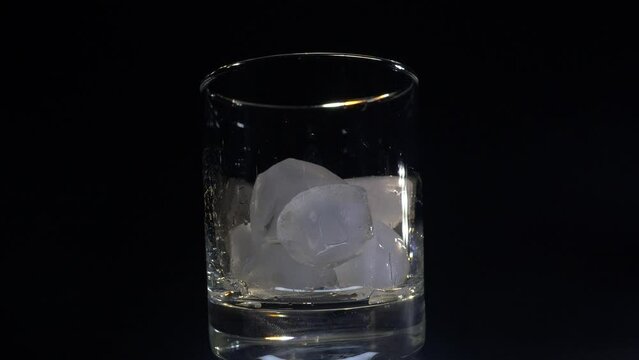 a man pours ice into a glass close-up on a dark background