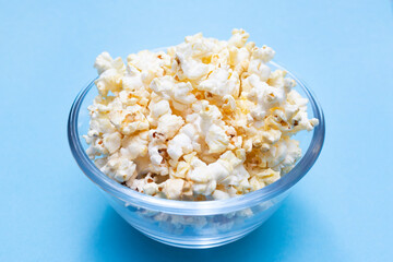 Popcorn on a blue background. Movie watching concept. Popcorn in a glass bowl for watching a movie and series