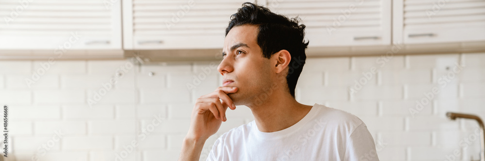 Sticker young hispanic man reading a book while having breakfast